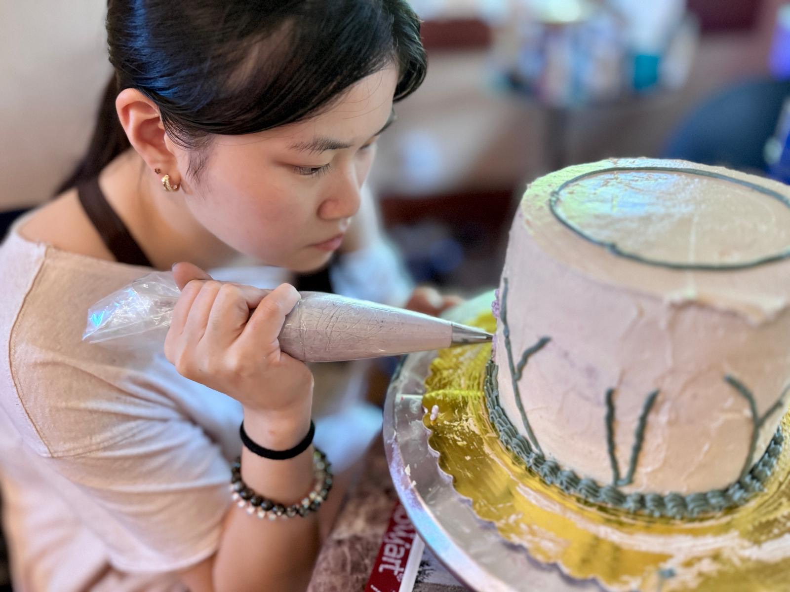 Zoe hand-piping buttercream details onto a cake