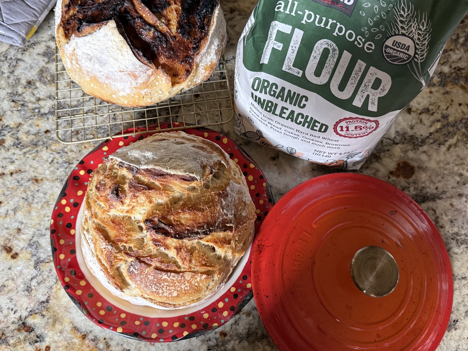 Two freshly baked sourdough loaves beside organic flour